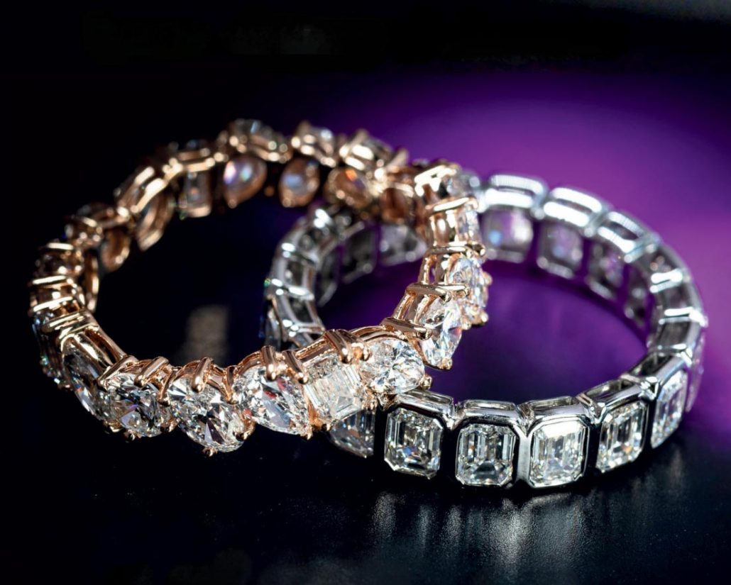 A set of husband-and-wife exquisite diamond wedding rings, lying on a dark blue countertop.