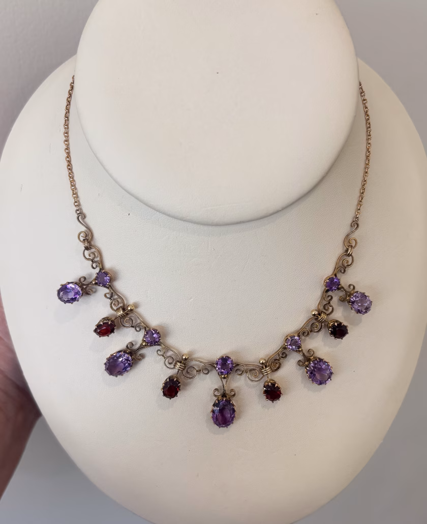 Victorian 9k gold necklace with alternating garnet and amethyst gemstones and ornate scrollwork.