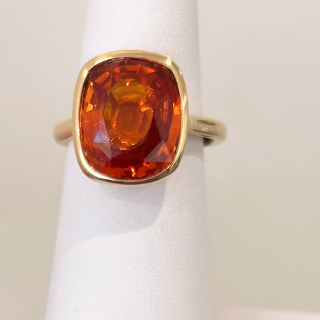 18K yellow gold ring with bezel set cushion cut orange sapphire